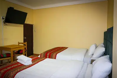 a hotel room with two beds and a flat screen tv at Cusco Hawka Pacha hostal in Cusco