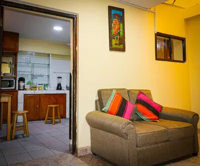 a living room with a couch and a kitchen at Cusco Hawka Pacha hostal in Cusco