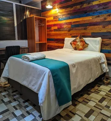 a bedroom with a bed with a wooden wall at Sumaq Wari Hotel in Ayacucho