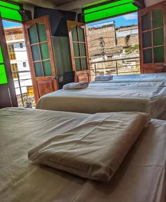 two beds in a room with green windows at Sumaq Wari Hotel in Ayacucho