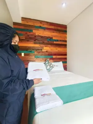 a person wearing a mask standing next to two beds at Sumaq Wari Hotel in Ayacucho