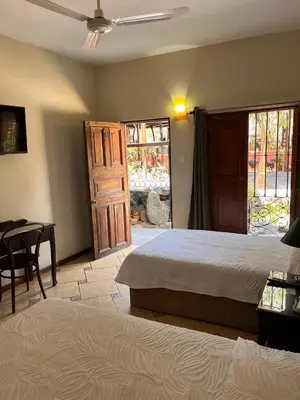 a bedroom with two beds and a table and a window at Hotel & Hacienda El Carmelo in Ica