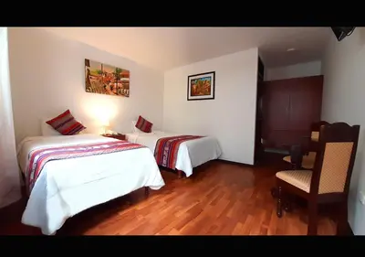 a hotel room with two beds and a chair at Hotel Santa Maria in Cusco