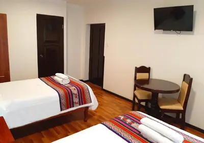 a room with two beds and a table and a television at Hotel Santa Maria in Cusco