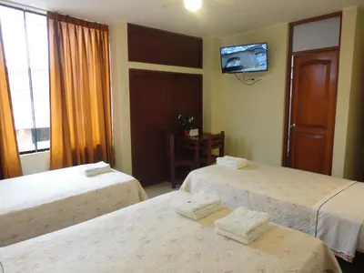 a hotel room with two beds and a tv on the wall at Hotel Torontel in Ica