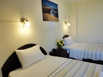 a hotel room with two beds and flowers on a table at Hotel Torontel in Ica