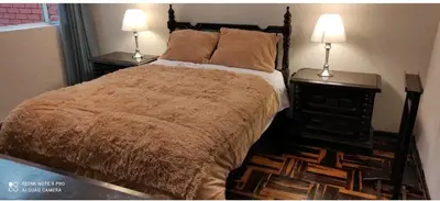 a bedroom with a bed and two lamps on tables at Habitación amoblada independiente dentro departamento amoblado tipo ROOMIE in Lima