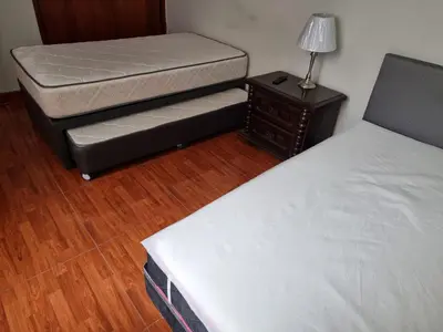 a bedroom with two beds and a nightstand with a bed and a lamp at Habitación amoblada independiente dentro departamento amoblado tipo ROOMIE in Lima