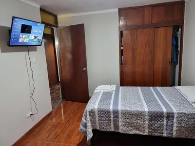 a bedroom with a bed and a tv on the wall at Habitación amoblada independiente dentro departamento amoblado tipo ROOMIE in Lima