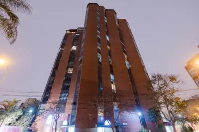 a tall brown building with lights on it at ALU Apartments - Miraflores in Lima