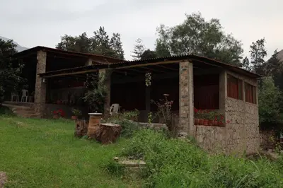 a small stone house in a field of grass at Cha'skas Checkta Eco-Lodge in Santa Rosa de Quives