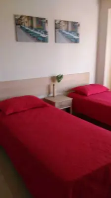 two beds in a room with red sheets at Hotel Kallma Adventures in Ica