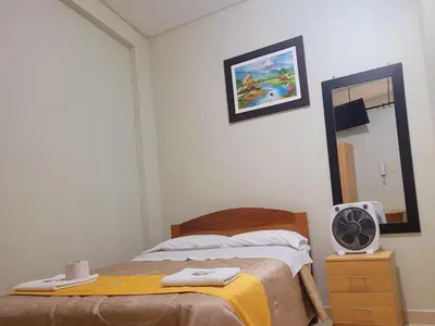 a bedroom with a bed and a mirror and a fan at Illari Wari II-Hotel Sauna in Ayacucho