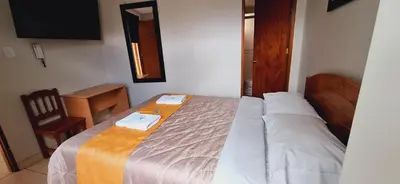 a bedroom with a bed with a table and a chair at Illari Wari II-Hotel Sauna in Ayacucho