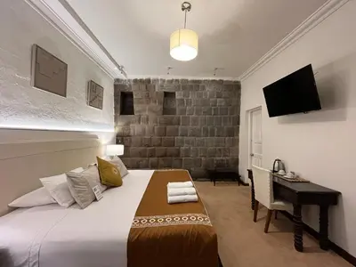 a bedroom with a bed and a desk and a television at Katari at Plaza de Armas Cusco in Cusco