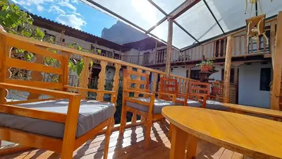 a balcony with wooden chairs and a table and a glass roof at Luisa in Ollantaytambo