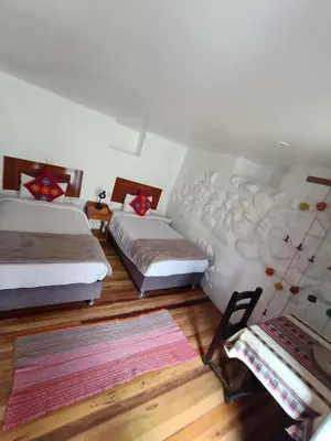 a bedroom with two beds and a table with a rug at Luisa in Ollantaytambo