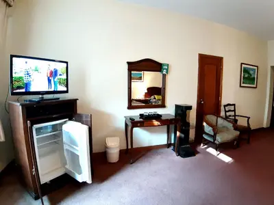a living room with a tv and a table and a mirror at Hotel MAURY in Lima