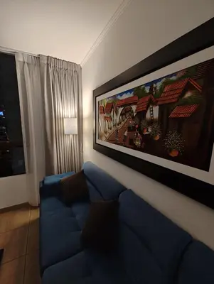 a living room with a blue couch and a painting on the wall at Dpto PARQUE SAN FELIPE in Lima