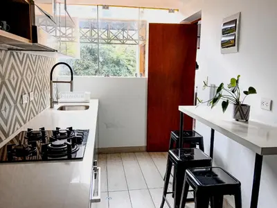 a kitchen with a stove and a counter with stools at Vistamar Duplex in Lima