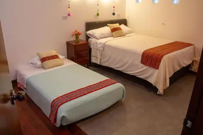 two beds in a hotel room with white sheets at Apartamento Altoandino in Ayacucho