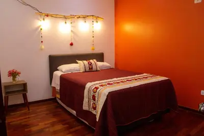 a bedroom with a bed with orange walls and lights at Apartamento Altoandino in Ayacucho