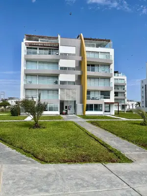 a large white building with a palm tree in front of it at Suite 1 Fila Vista Bahía Paracas- La Velas 601 T1 in Paracas