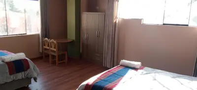 a bedroom with a bed and a table and a chair at Maychu's Albergue in Chinchero