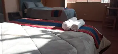 a bed with two rolls of towels on it at Maychu's Albergue in Chinchero