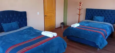 a hotel room with two beds with blue covers at Maychu's Albergue in Chinchero