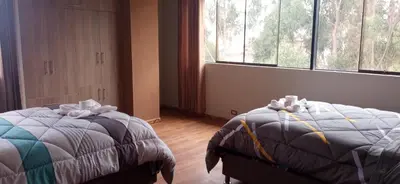 a bedroom with two beds and a large window at Maychu's Albergue in Chinchero