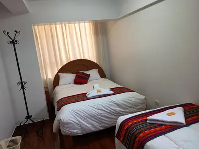 a small bedroom with two beds and a window at Hotel TIKA AYNA Cerca a la plaza de Armas CUSCO in Cusco