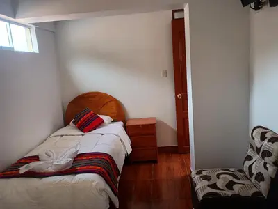 a small bedroom with a bed and a chair at Hotel TIKA AYNA Cerca a la plaza de Armas CUSCO in Cusco