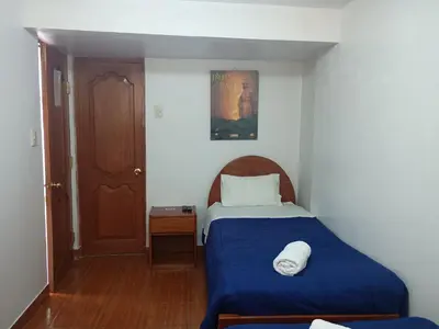 a small bedroom with a bed with a blue blanket at Hotel TIKA AYNA Cerca a la plaza de Armas CUSCO in Cusco