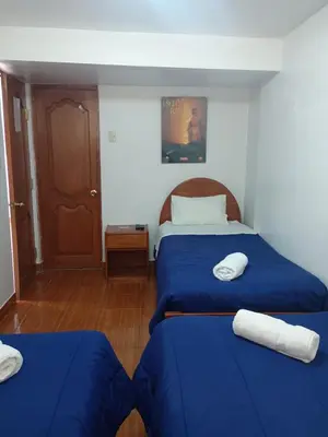 two beds in a room with blue sheets and white towels at Hotel TIKA AYNA Cerca a la plaza de Armas CUSCO in Cusco
