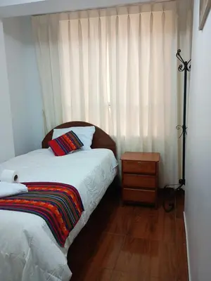 a bedroom with a bed and a window with curtains at Hotel TIKA AYNA Cerca a la plaza de Armas CUSCO in Cusco