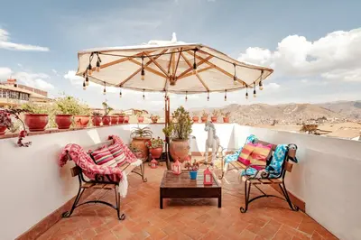a balcony with two chairs and an umbrella at Andenes in Cusco