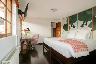 a bedroom with a bed and a desk and a window at Andenes in Cusco