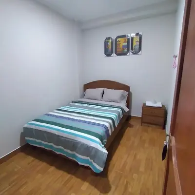 a bedroom with a bed and a wooden floor at Hostal Pacífico Huánuco in Huánuco