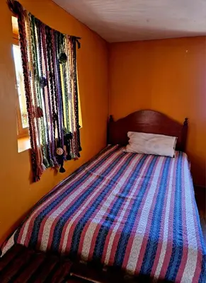 a bedroom with a bed with a striped comforter at KanchayKillaWasi in Chinchero