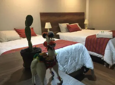 two dolls in a hotel room with two beds and a cactus at Hotel Vista Verde in Huancayo
