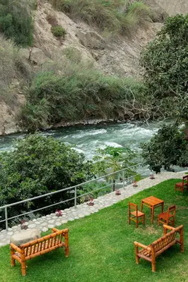 two benches and a table next to a river at Hotel Rumi Wasi in Lunahuaná