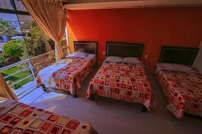 three beds in a room with a balcony at Hotel Rumi Wasi in Lunahuaná