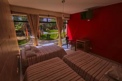 a hotel room with two beds and a window at Hotel Rumi Wasi in Lunahuaná