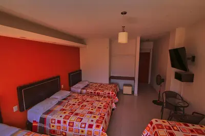two beds in a hotel room with red walls at Hotel Rumi Wasi in Lunahuaná