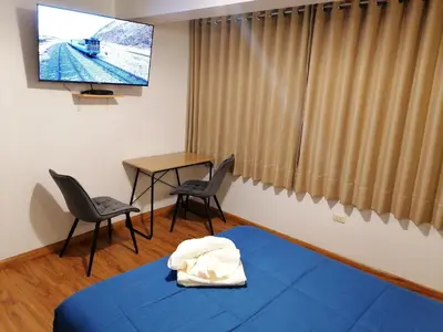 a room with a tv and a bed and chairs at El Ave Azul Boutique Hotel Cusco in Cusco