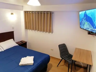 a bedroom with a bed and a table and a tv at El Ave Azul Boutique Hotel Cusco in Cusco