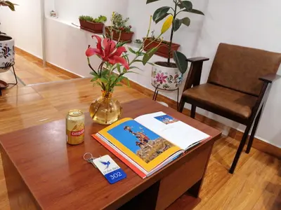 a table with a book and a vase with flowers at El Ave Azul Boutique Hotel Cusco in Cusco