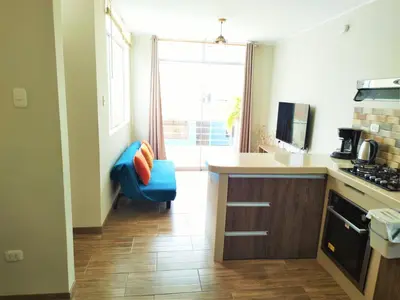 a kitchen with a blue chair and a window at Departamento Hermoso en Residencial - Huacachina in Ica