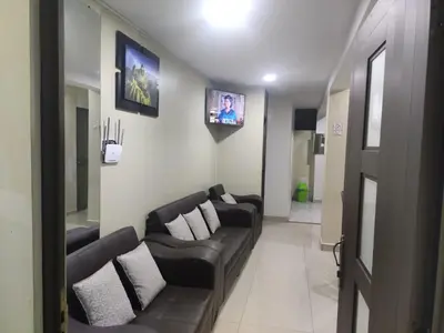 a living room with black leather couches and a tv at Depawanka 1 departamento amoblado in Huancayo
